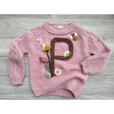 a pink sweater with flowers on it and the letter p in brown is knitted