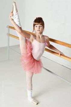 a young ballerina is posing for the camera