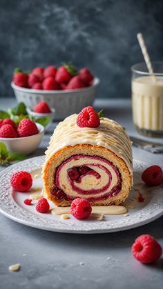 a cake roll with raspberries and cream frosting on a plate next to some strawberries