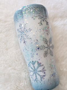 a blue and white snowflaked tumbler sitting on top of a fur covered floor