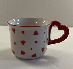 a red and white coffee cup with hearts on it