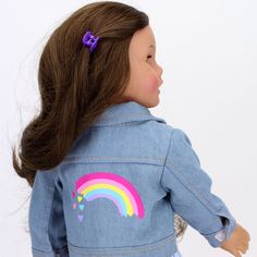 a doll wearing a denim jacket with a rainbow painted on it's chest and back