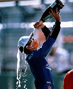 a man in blue shirt pouring champagne on his head