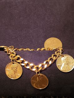 a gold bracelet with five different coins on it