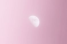 the moon is shining in the pink sky