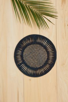 a round woven placemat on a wooden surface with a palm tree in the background