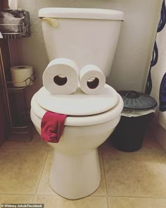 a white toilet with two rolls of toilet paper on it's lid and eyes