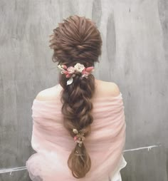 a woman with long hair wearing a pink dress and flowers in her hair is standing against a wall