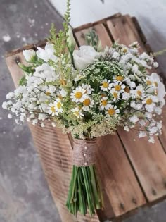 a bouquet of daisies and other flowers in a vase on top of a wooden crate