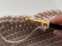 someone is crocheting the ends of a knitted blanket with a yellow needle