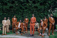 a group of men in orange suits standing next to each other on a brick walkway