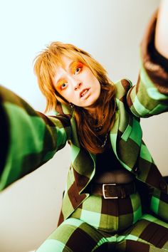 a woman in green and black checkered suit posing for the camera