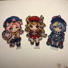 three cross stitch characters are displayed on a table