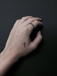 a person's hand with a cross tattoo on it