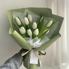 a bouquet of white tulips wrapped in green paper