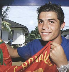 a young man holding up a soccer jersey