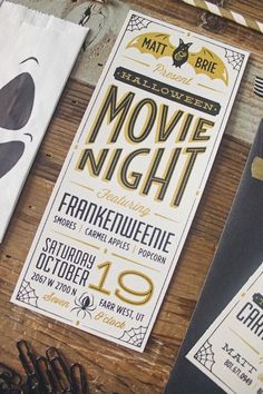 two halloween movie night flyers on a wooden table with scissors and other items around them