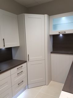 an empty kitchen with white cabinets and black counter tops on both sides, along with dark wood flooring