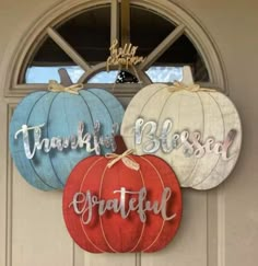 three pumpkins hanging on the front door of a house with words painted on them