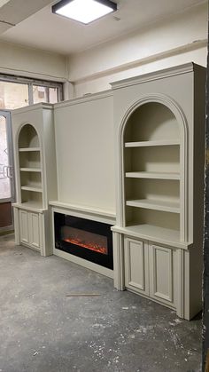 an empty room with built in shelves and a fire place