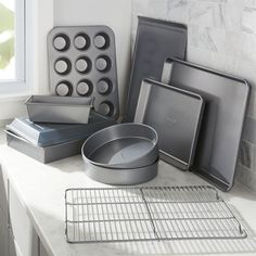 various pans and baking utensils sitting on a counter top next to a window