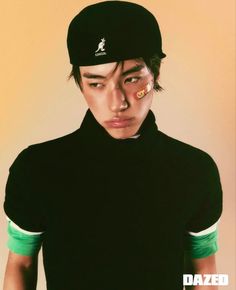 a young man wearing a black hat and green shirt with the word dazed on his forehead