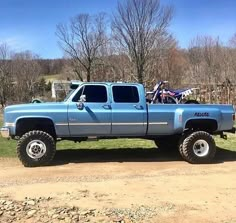 a blue truck parked on top of a dirt road