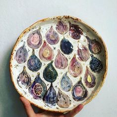 a hand holding a bowl with different types of seashells on it