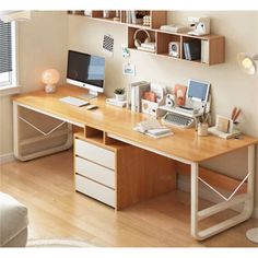 a computer desk with two computers on top of it and shelves above the desk, along with other office supplies