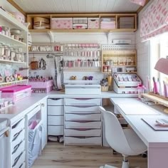 a kitchen with lots of drawers and white counter tops, along with pink accessories on shelves