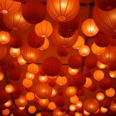 many red lanterns are lit up in the air and hanging from the ceiling with lights on them