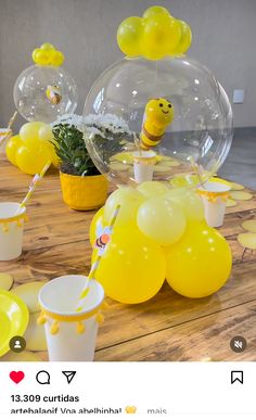 a table topped with balloons and cups filled with yellow liquid, sitting on top of a wooden table