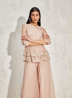 Editor's Note Blush scallop flora peplum and sharara is an elegant ethnic wear set, made of lightweight organza fabric. The peplum top features a beautiful floral embellishment and a scallop hemline. The set includes a pair of sharara pants with a flared silhouette. Color: Blush Fabric: Organza Component: Peplum and sharara Occasion: Cocktail and wedding guest Embroidery: Floral hand & machine embellishment Disclaimer: Product color may slightly vary due to photographic lighting sources or your Blush Fabric, Sharara Pants, Floral Embellishment, Embroidery Floral, Color Blush, Organza Fabric, Photographic Lighting, Rococo, Ethnic Wear