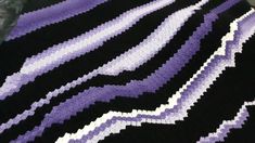 a purple and black blanket sitting on top of a bed