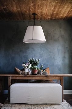 a dining room table with flowers on it and a lamp hanging from the ceiling above