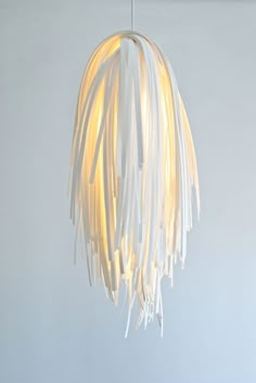 a white light hanging from a ceiling fixture with fringes on it's sides