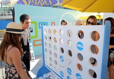 a group of people standing around a giant board game at an outdoor event in the sun