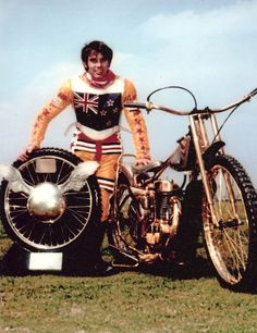 a man standing next to a motorcycle on top of a field