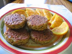 some food is sitting on a plate with oranges and other foods around it, including meat patties