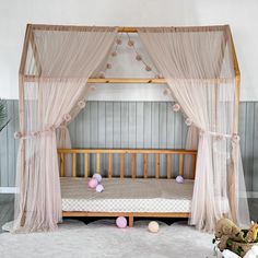 a canopy bed with pink and white decorations on the floor next to a potted plant