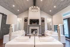 a living room with white couches and a fire place in the middle of it