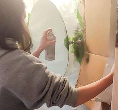 a woman is painting a mirror with green paint