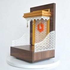 a wooden clock with white and brown designs on it's face, sitting on top of a shelf