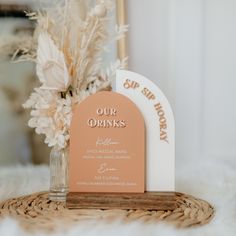 an orange and white menu sitting on top of a table next to a vase filled with flowers