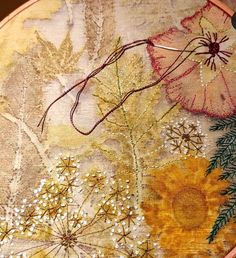 an embroidery project with flowers and leaves on the side of a wooden tablecloth covered in sequins