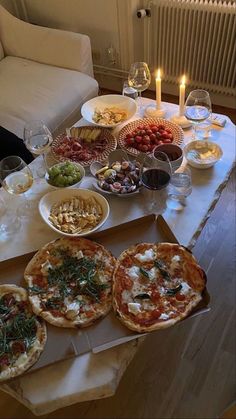 pizzas and other food on a table with candles