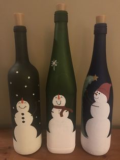 three wine bottles with snowmen painted on them