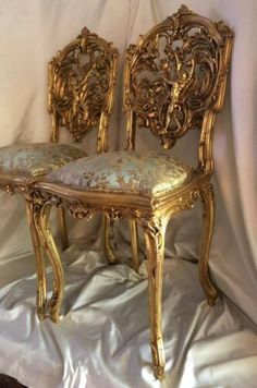 two golden chairs sitting on top of a white sheet