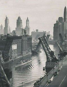 an old black and white photo of a bridge over a river in the middle of a city