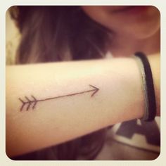 a woman's arm with an arrow tattoo on the left side of her arm